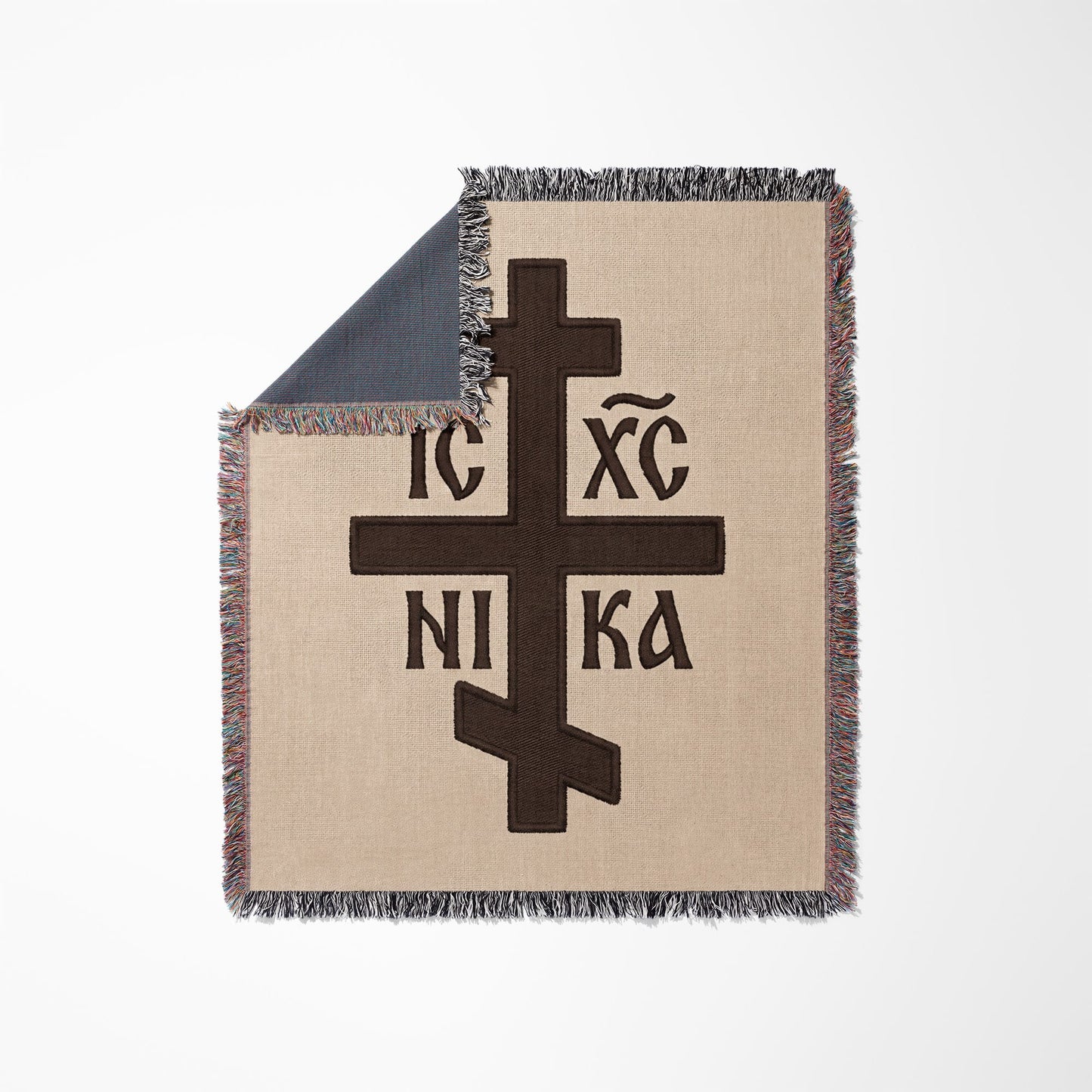 Brown Orthodox cross with Greek lettering on a beige woven throw blanket.