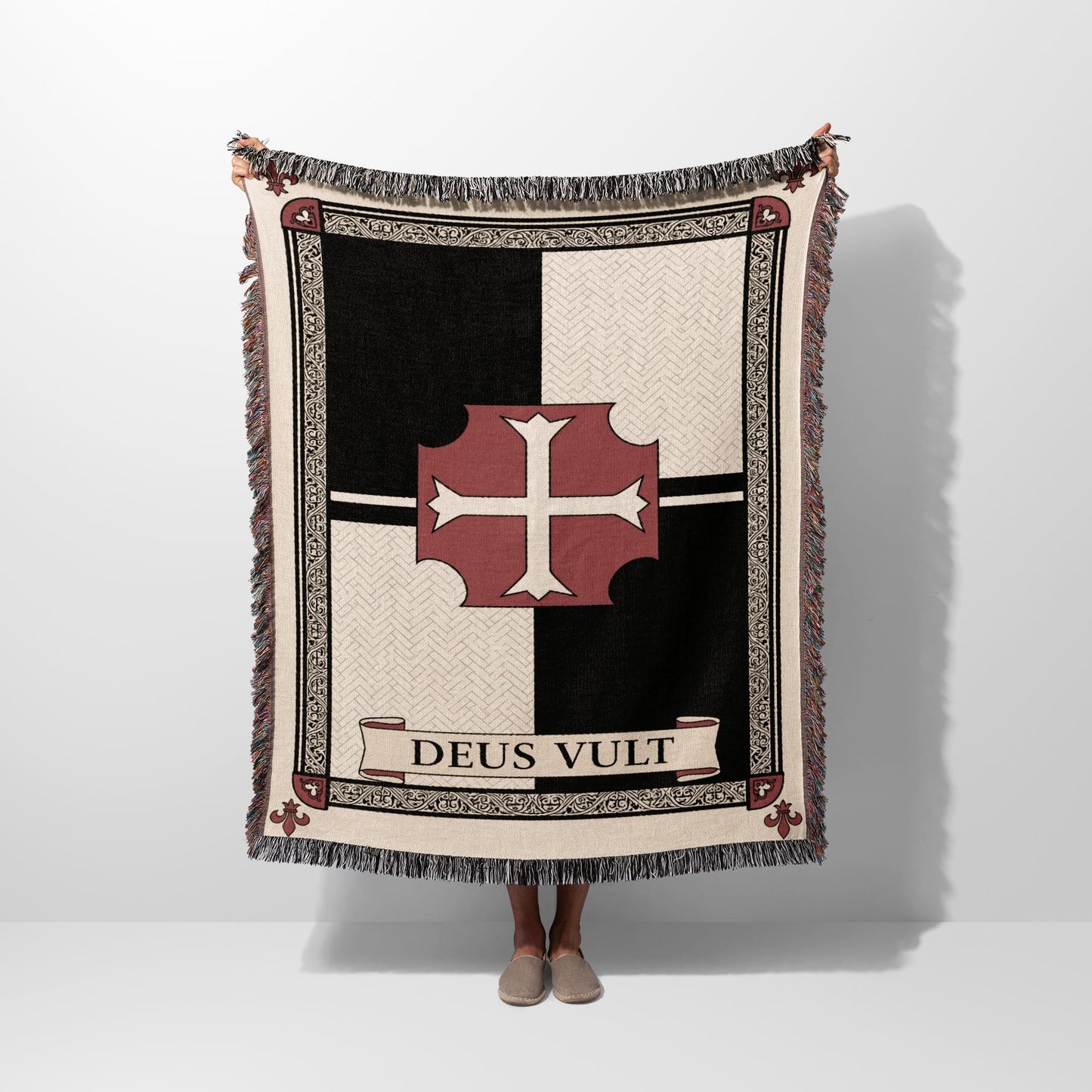 Tapestry blanket with red cross and "DEUS VULT" text, held by person.