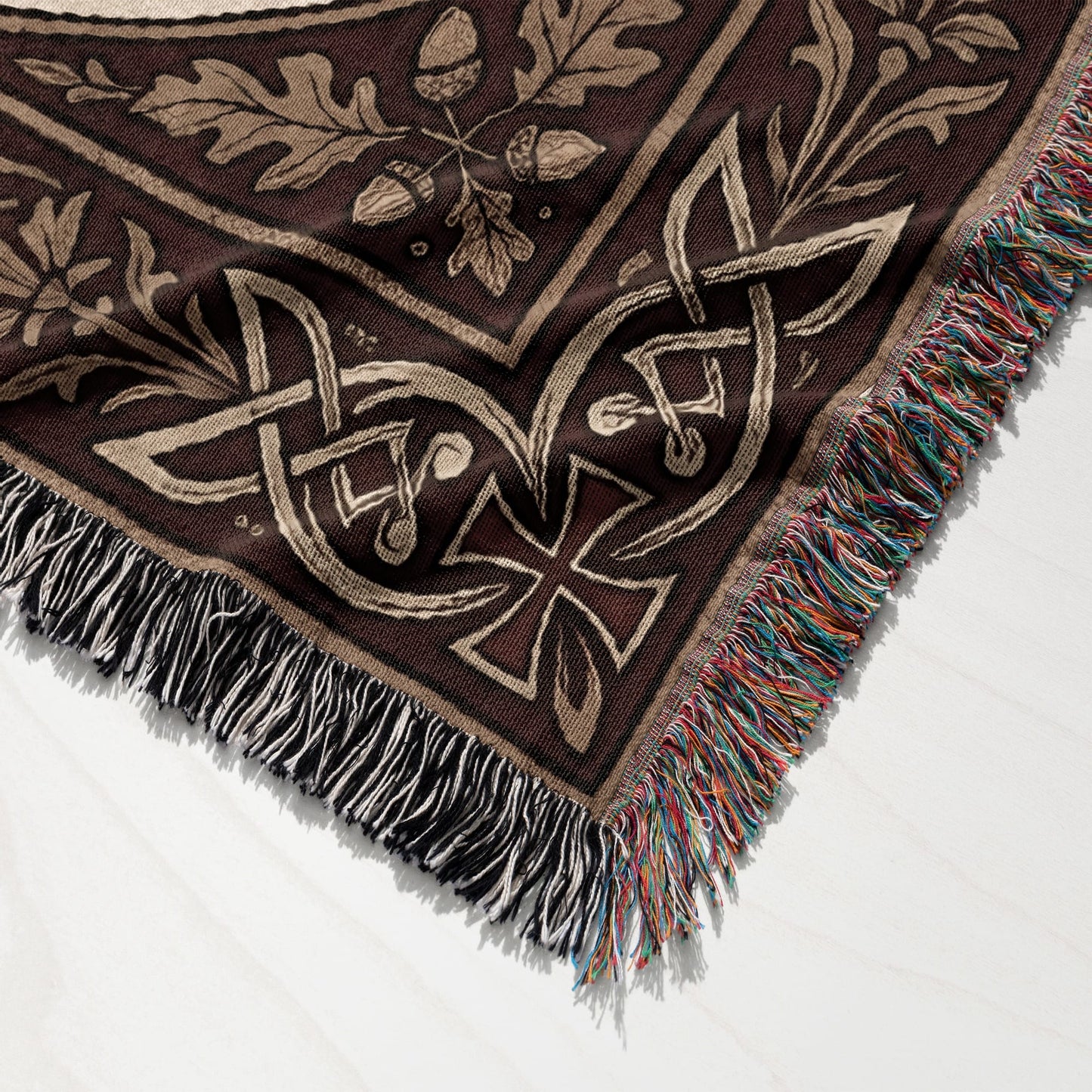 Brown woven throw with Celtic knot, oak leaf, and acorn pattern and fringed edges.