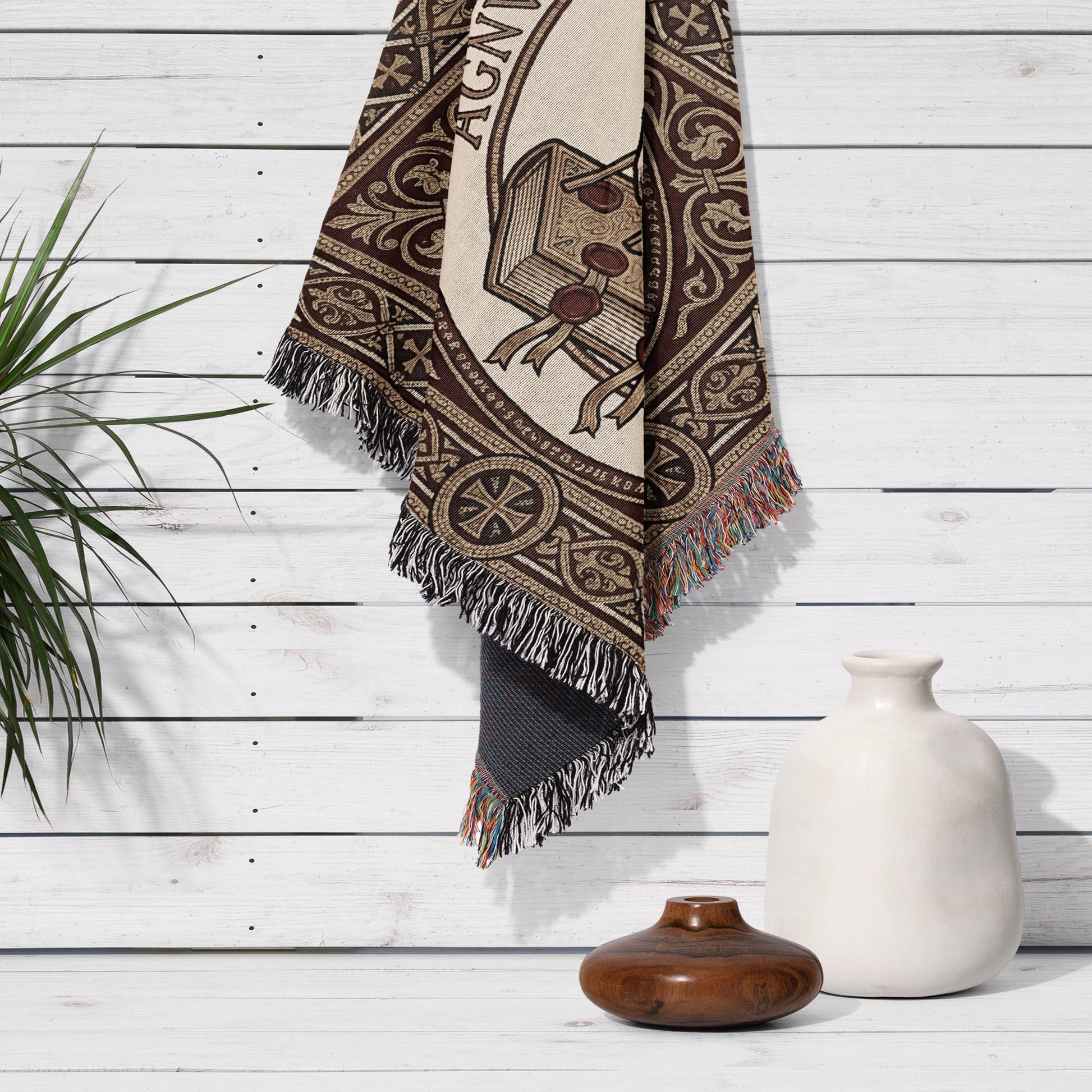 Tapestry with "AGNI" text hanging on a white wood-paneled wall with vase.