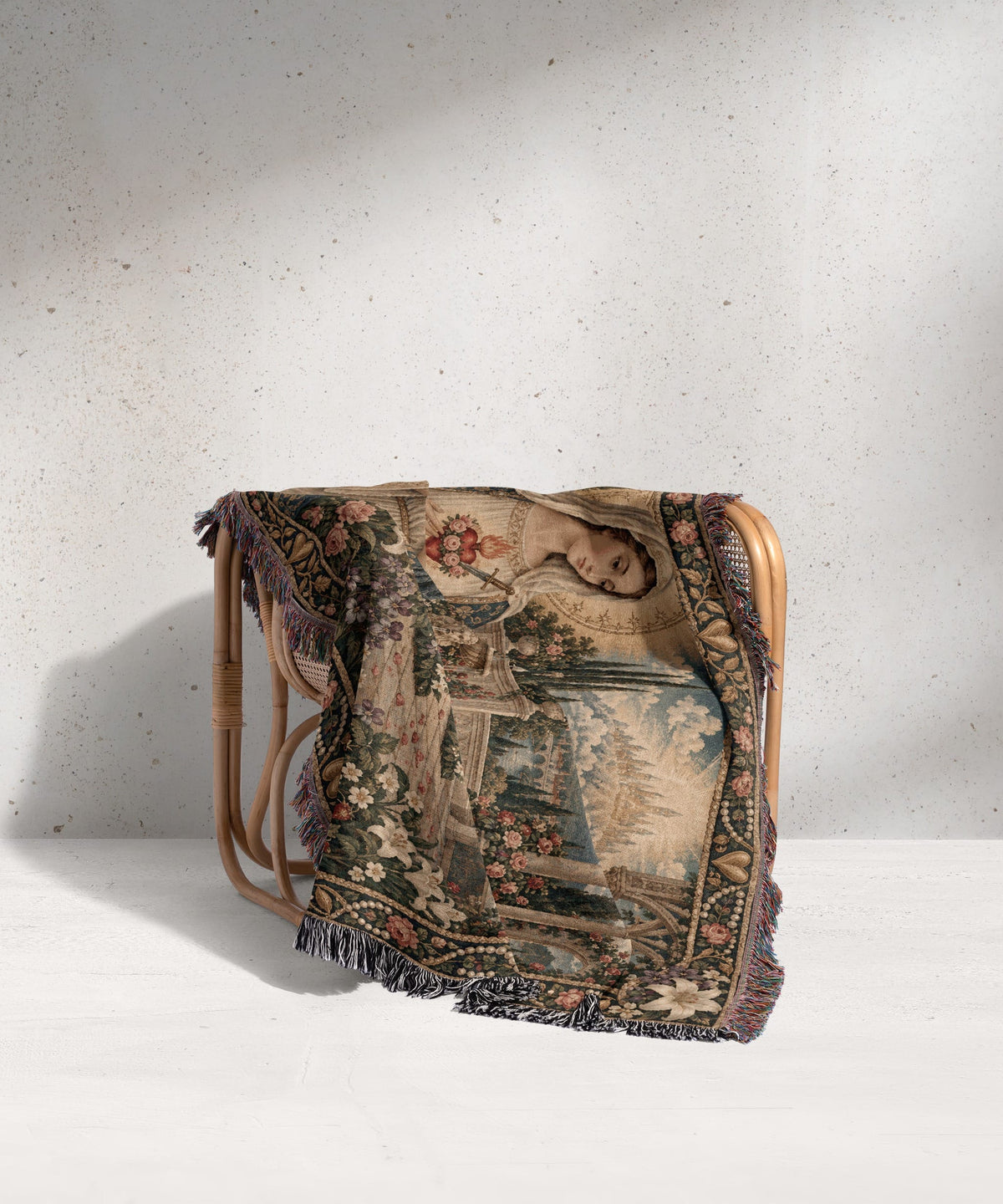 A woven tapestry throw blanket featuring a classic renaissance portrait draped over a rattan chair.