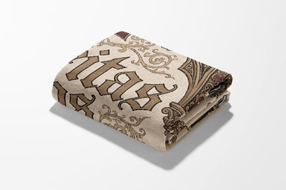 Folded blanket with ornate gothic text and scrollwork pattern in brown and tan.