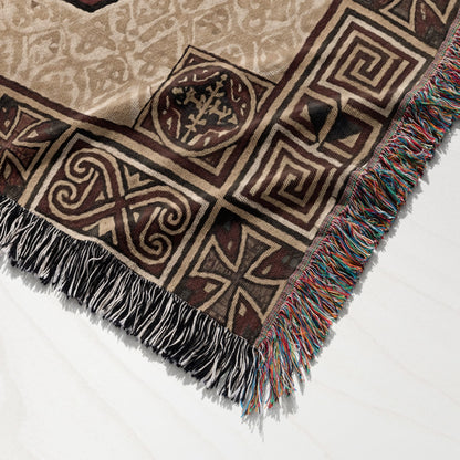 Woven blanket with Celtic knot patterns and fringe detail on white surface.