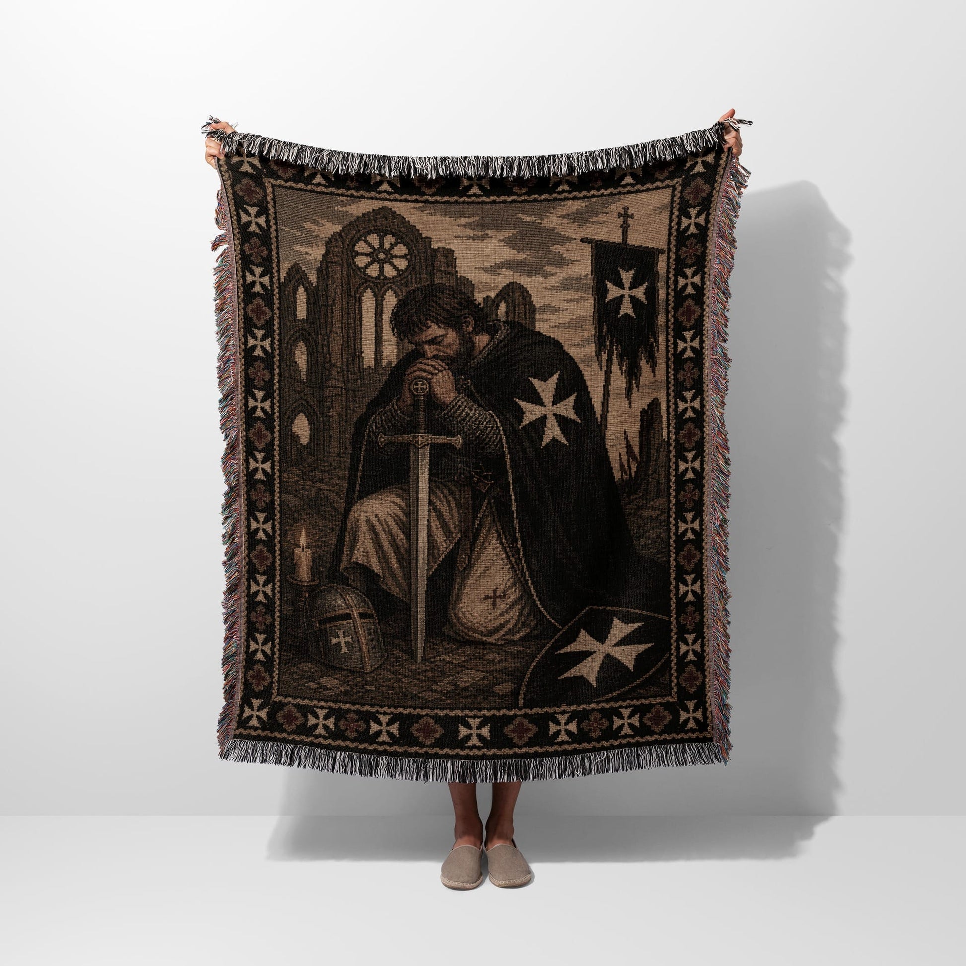 Knight kneeling with sword, wearing crusader cross, holding tapestry blanket.