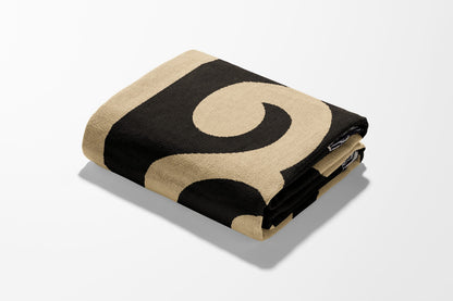 Folded beige and black patterned blanket on white background.