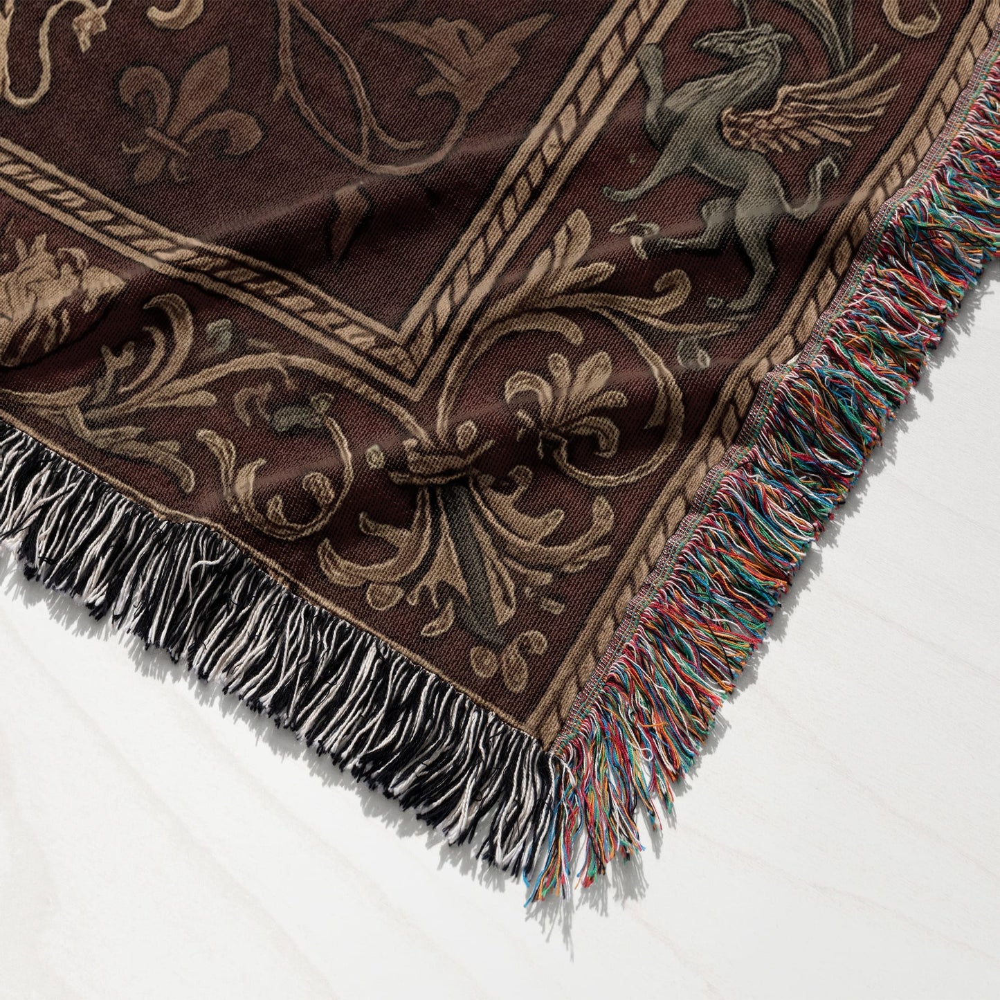 Brown tapestry throw with winged mythical creature and ornamental border, tasseled edges.