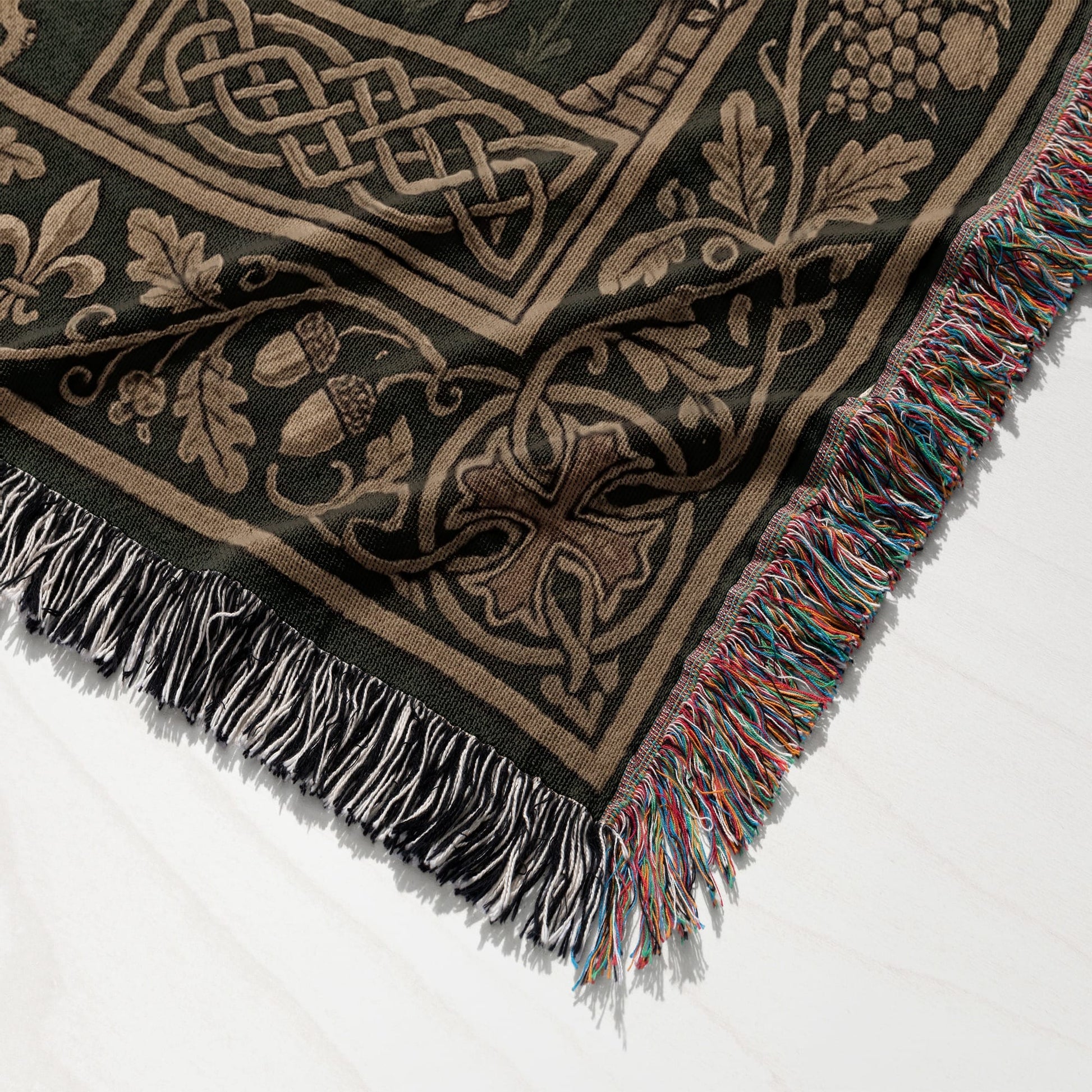 Woven blanket with Celtic knot, oak leaf, acorn, and fleur-de-lis design, and tasseled edges.
