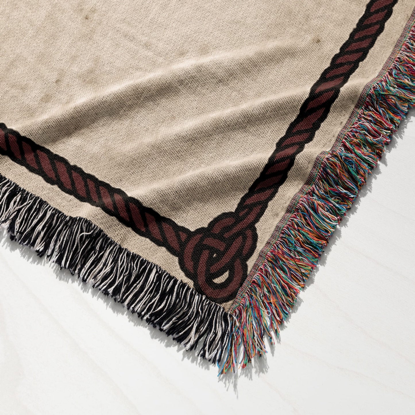 Woven blanket with a dark brown rope knot border and fringed edges.