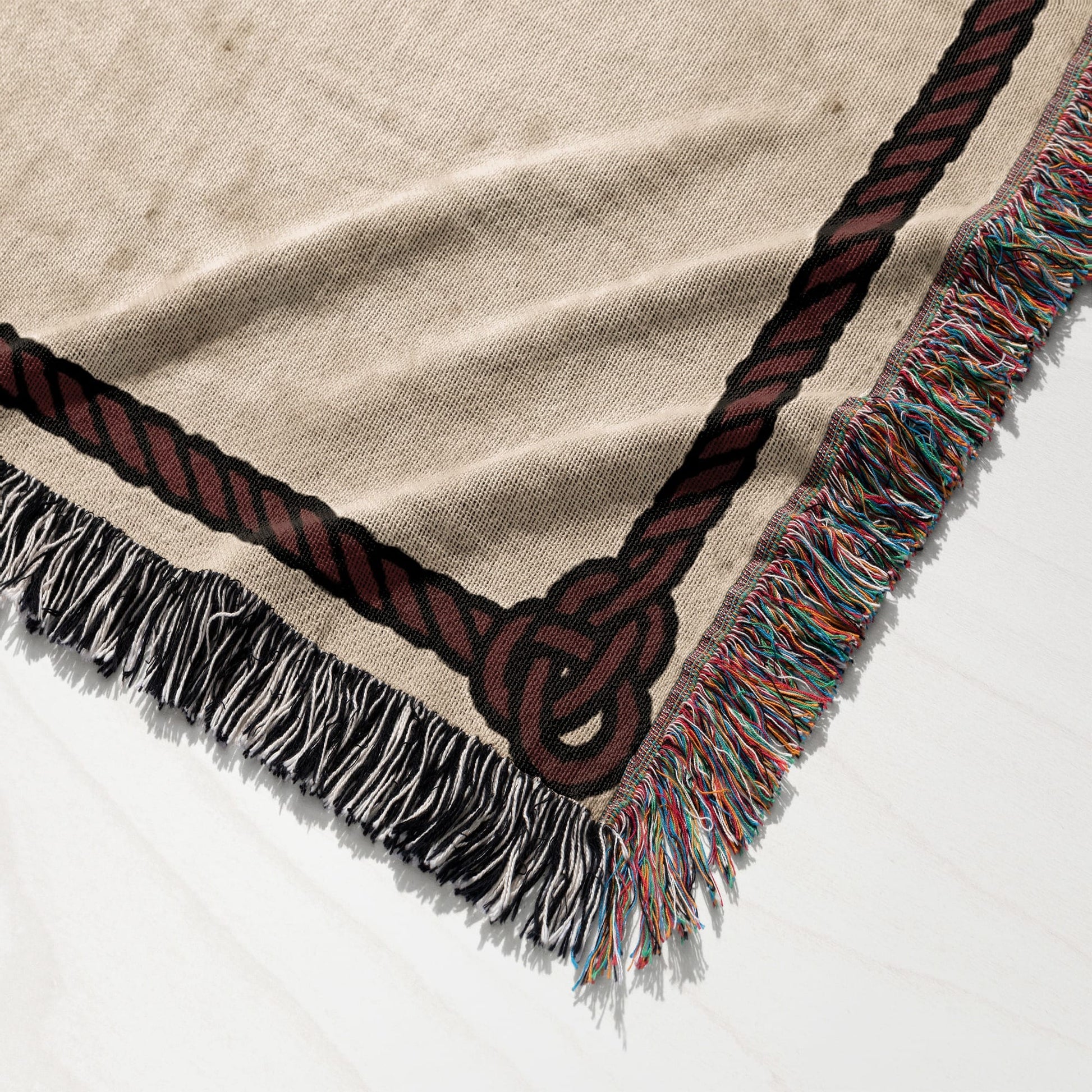 Woven blanket with a dark brown rope knot border and fringed edges.
