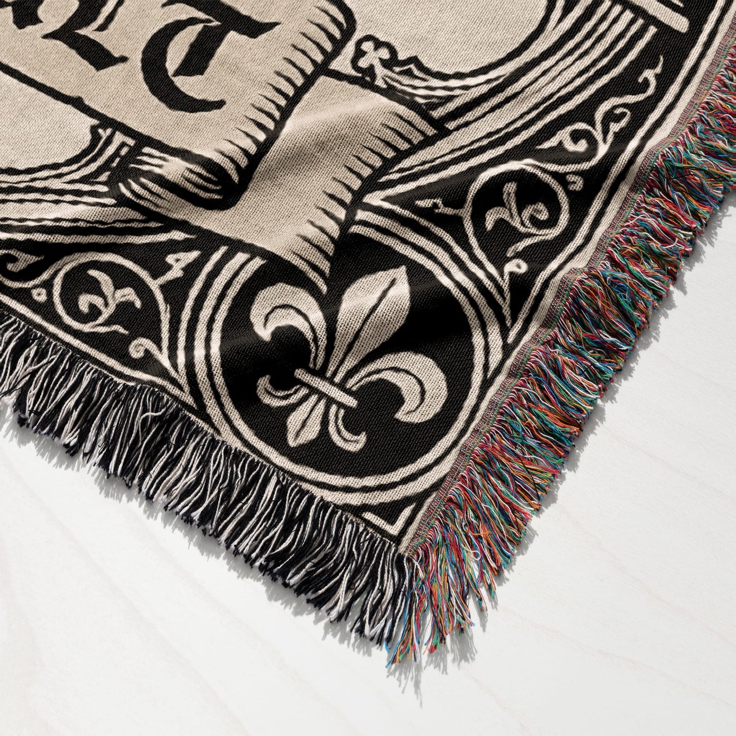 Woven blanket with fleur-de-lis and ornate black and cream border.