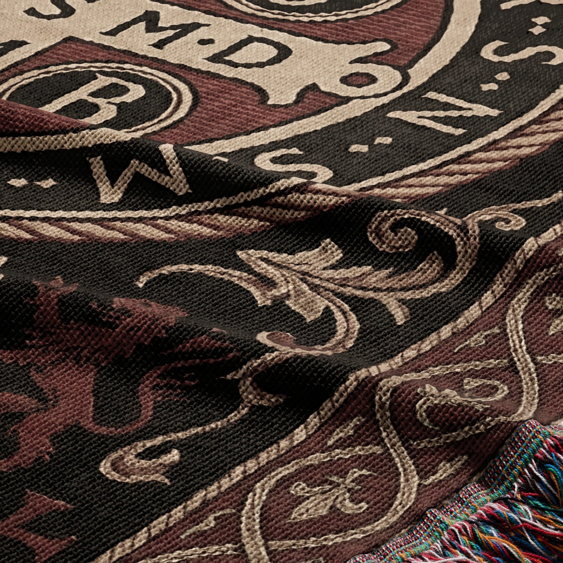 Woven blanket with dark red, black, and cream heraldic crest and fringed edge.
