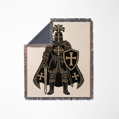 Knight in armor with shield and sword on a patterned blanket.