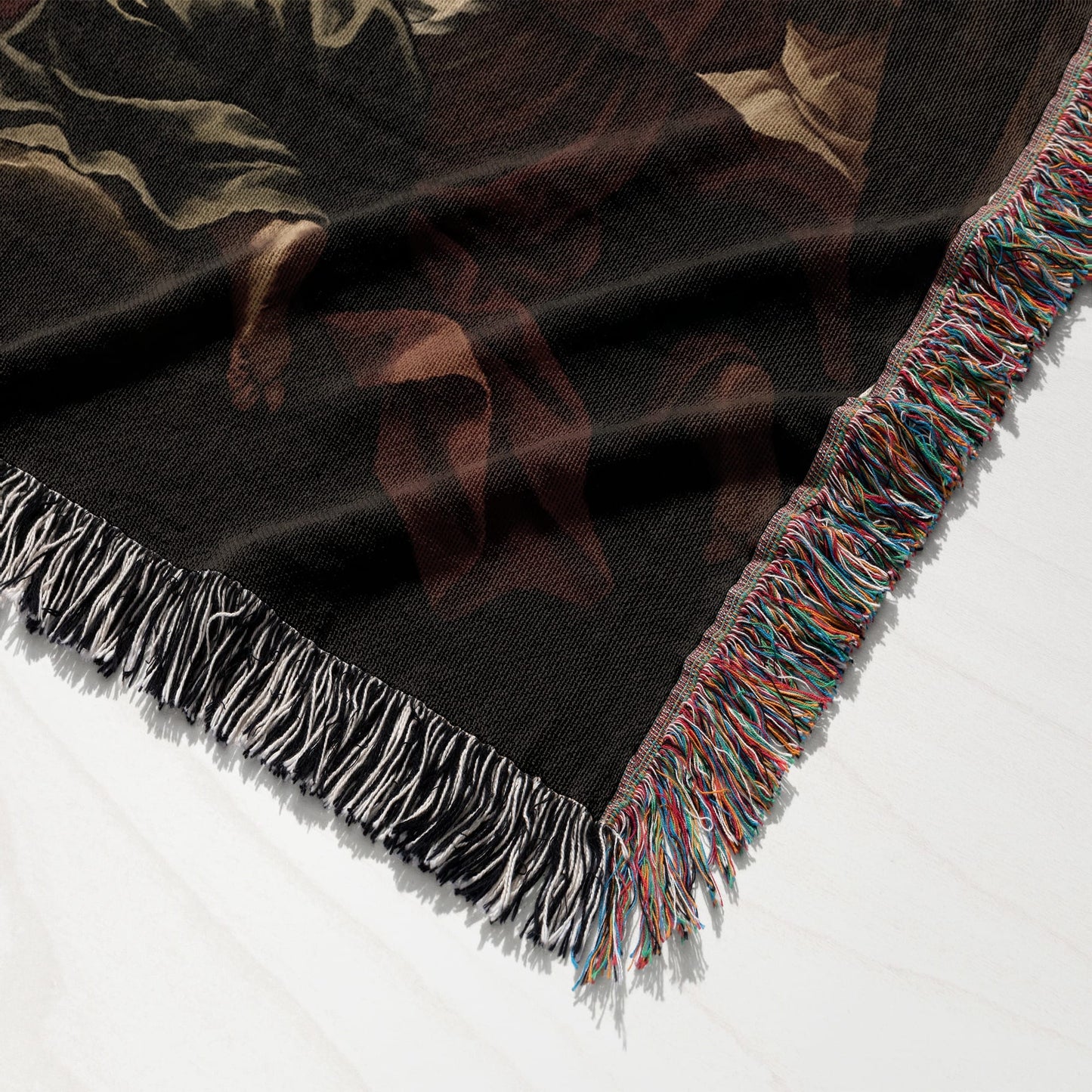 Close-up of a dark blanket with a colorful fringed edge and abstract pattern.
