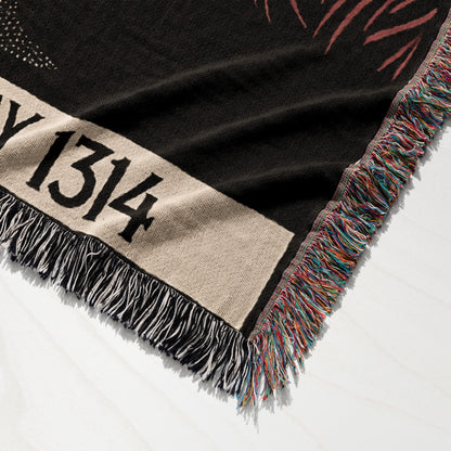 Black throw blanket with tan band and "Y 1314" text, fringed edges.