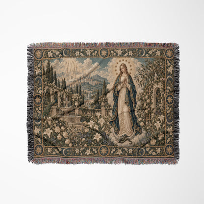 A woven tapestry blanket featuring a religious scene with a woman standing amid flowers and a distant city.