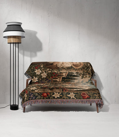 A wooden sofa draped with a floral tapestry featuring pomegranates and lilies next to a modern floor lamp against a textured white wall.