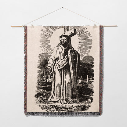 Black and white tapestry depicting Jesus Christ carrying a cross, with sunburst rays.