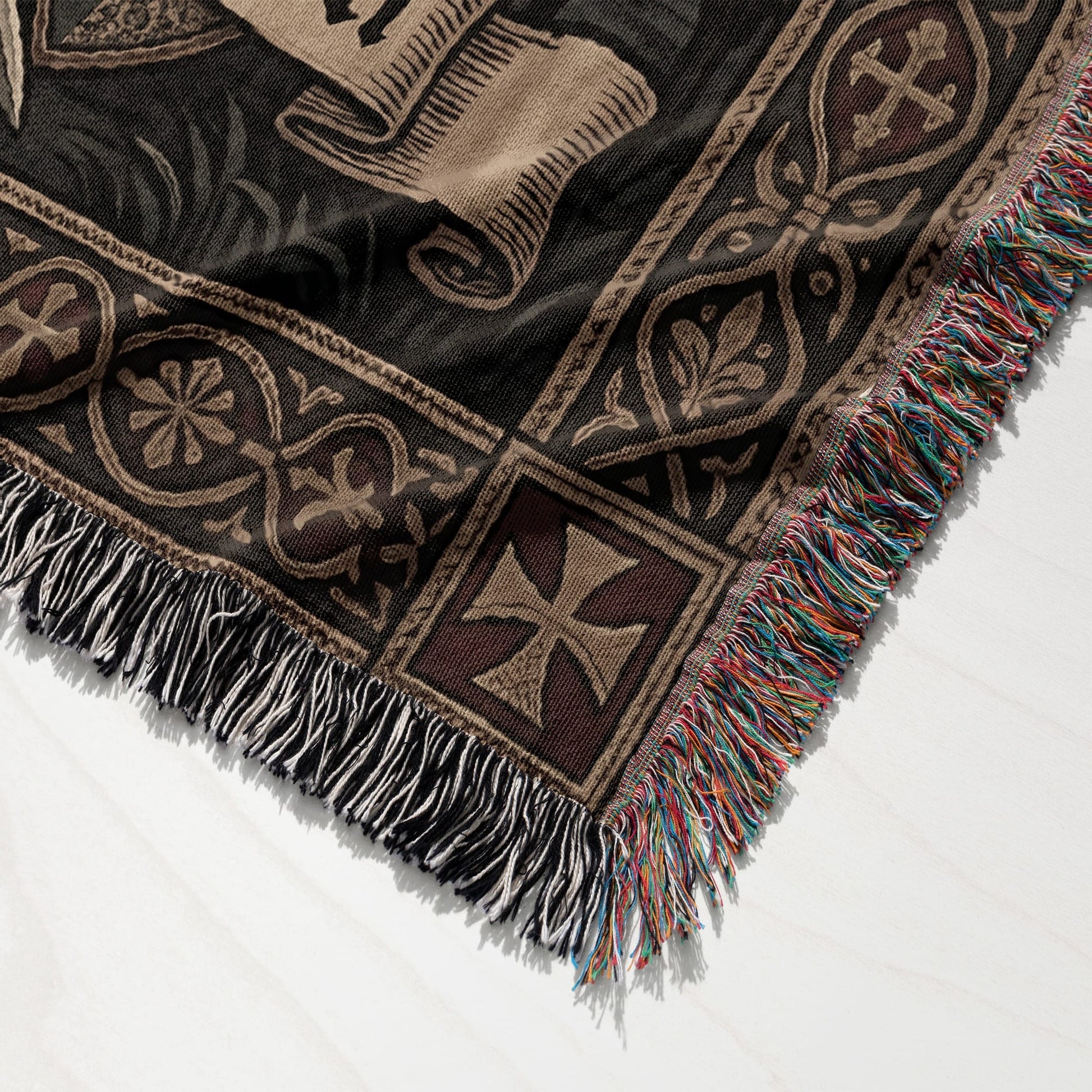 Woven blanket with fringe, featuring a medieval scroll and cross design.