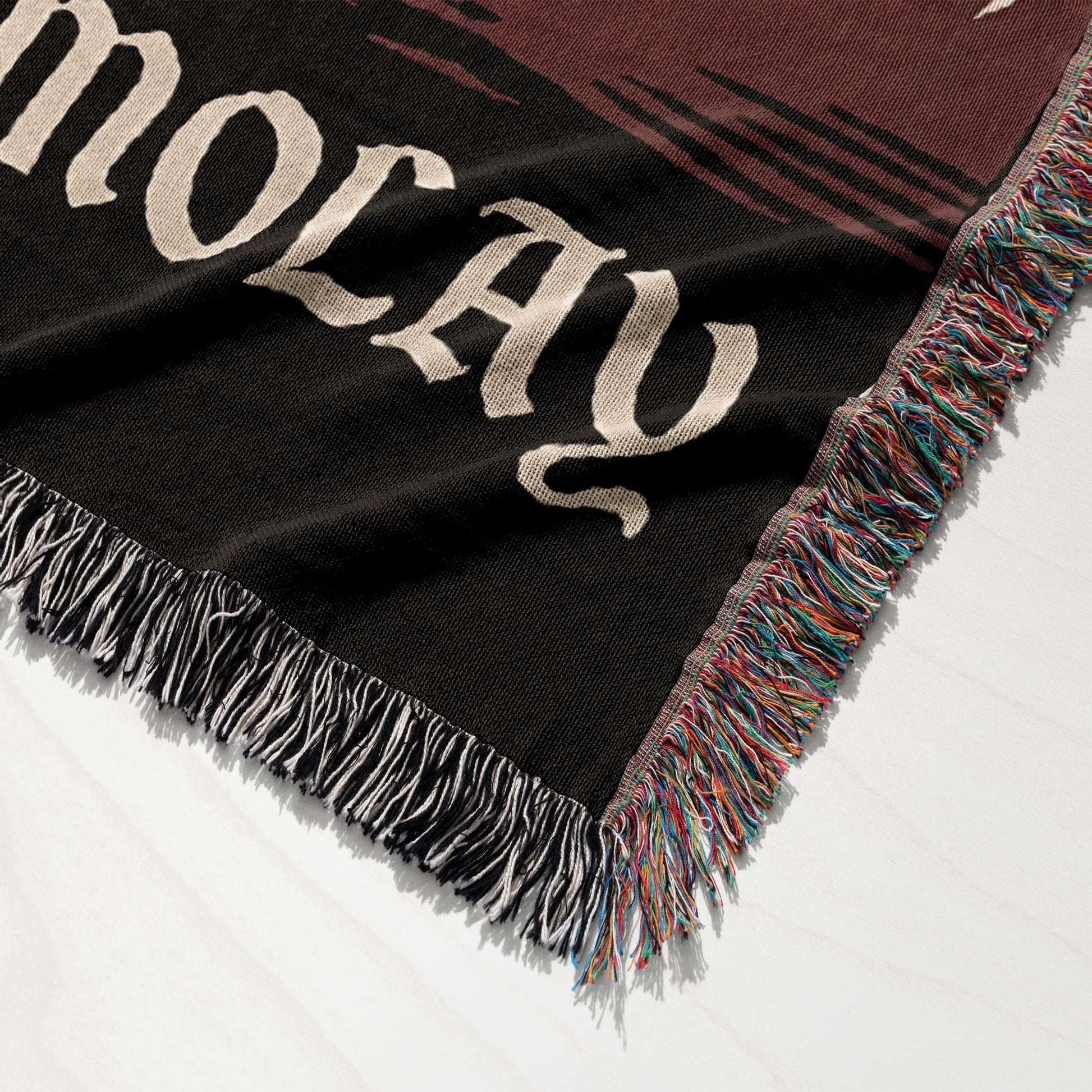 Black woven throw blanket with fringe, displaying the word "HOLIDAY" in large cream lettering.