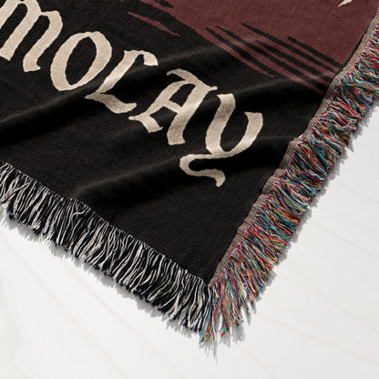 Black woven throw blanket with fringe, displaying the word "HOLIDAY" in large cream lettering.