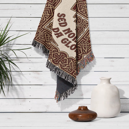Woven tapestry with ornate pattern and "SED NO GLORIA" text hanging on white wood wall.