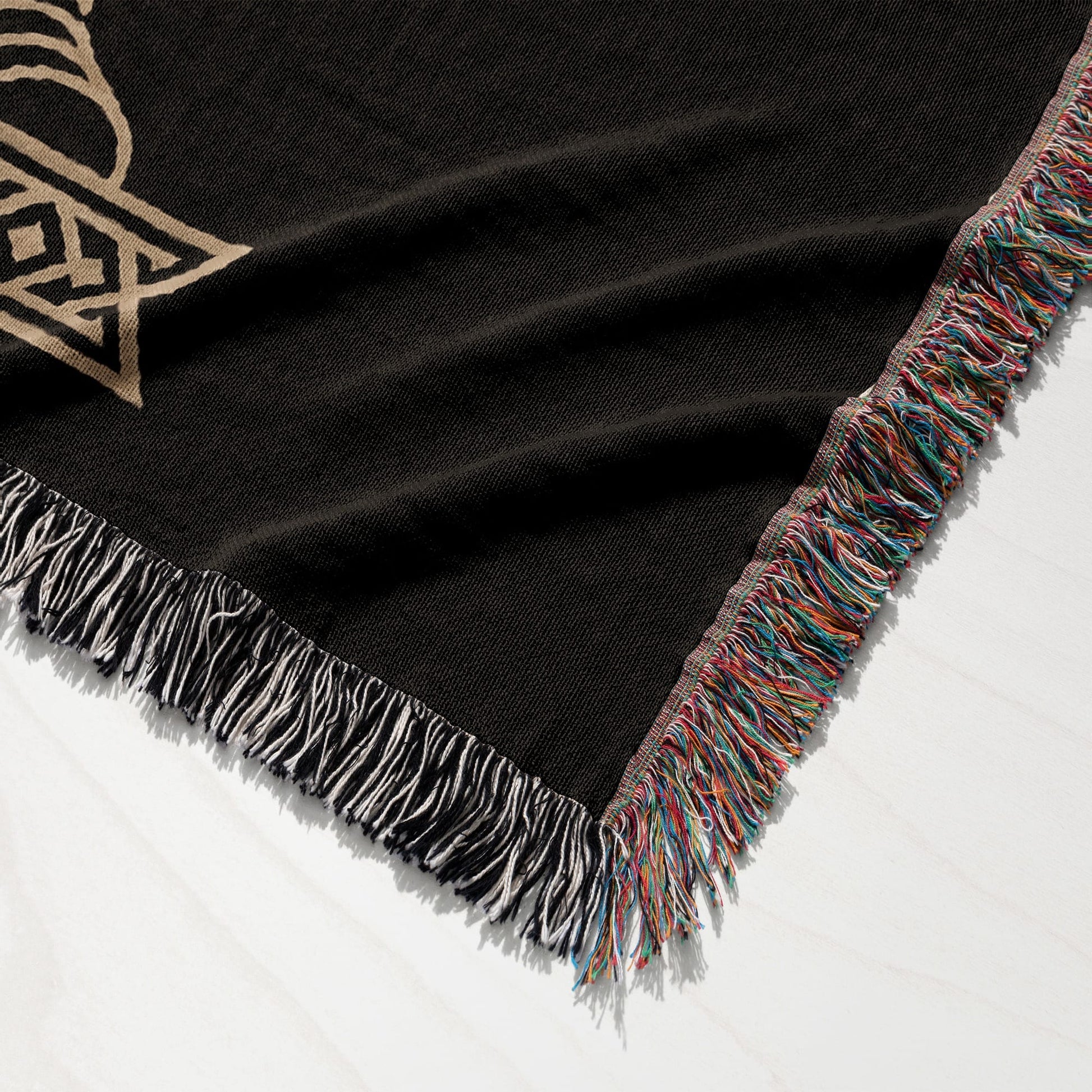 Black woven throw blanket with tasseled edges and a gold Celtic knot pattern.
