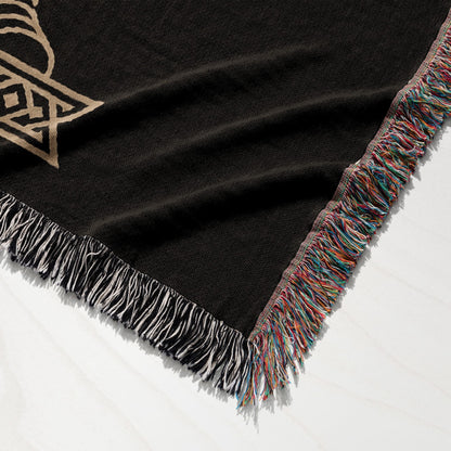 Black woven throw blanket with tasseled edges and a gold Celtic knot pattern.
