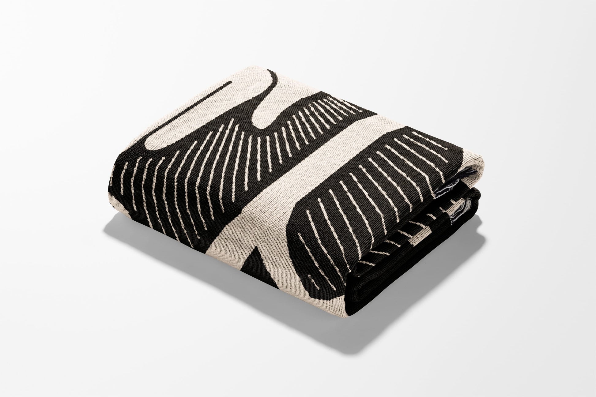 Folded black and white patterned throw blanket with a minimalist design.