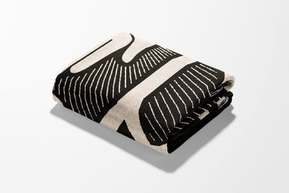 Folded black and white patterned throw blanket with a minimalist design.