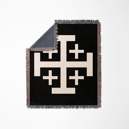 Black woven blanket with a cream Jerusalem cross design and frayed edges.