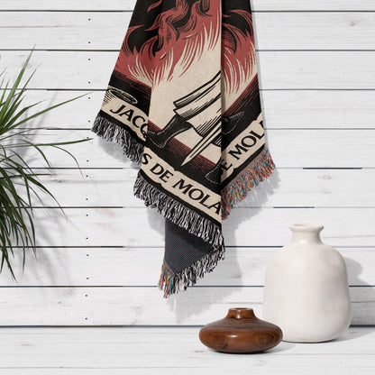 Woven blanket with "JACQUES DE MOLA" text and fringed edges hangs on a wall.