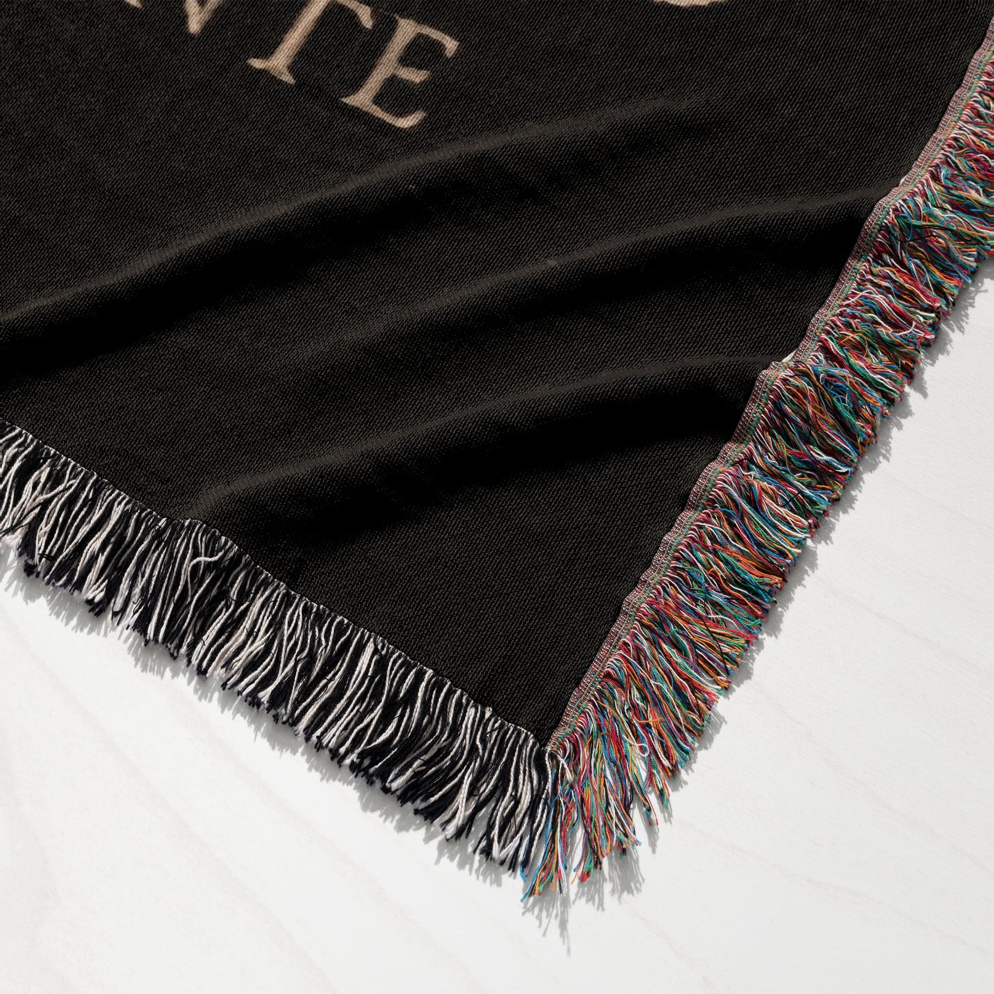 Black throw blanket with fringed edges in multicolor yarn.