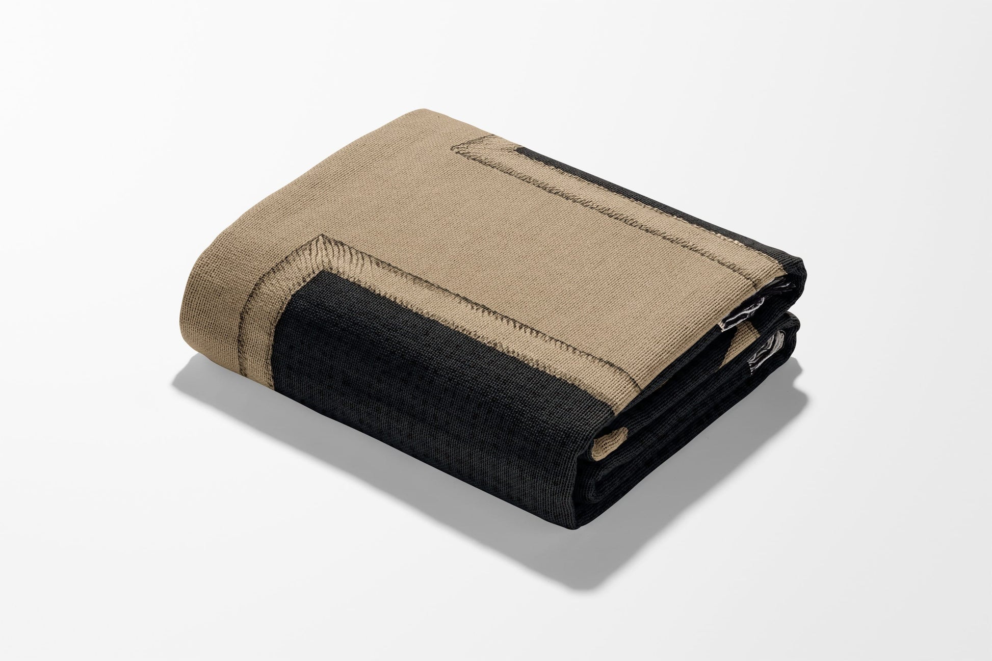 Folded tan and black throw blanket with textured trim.