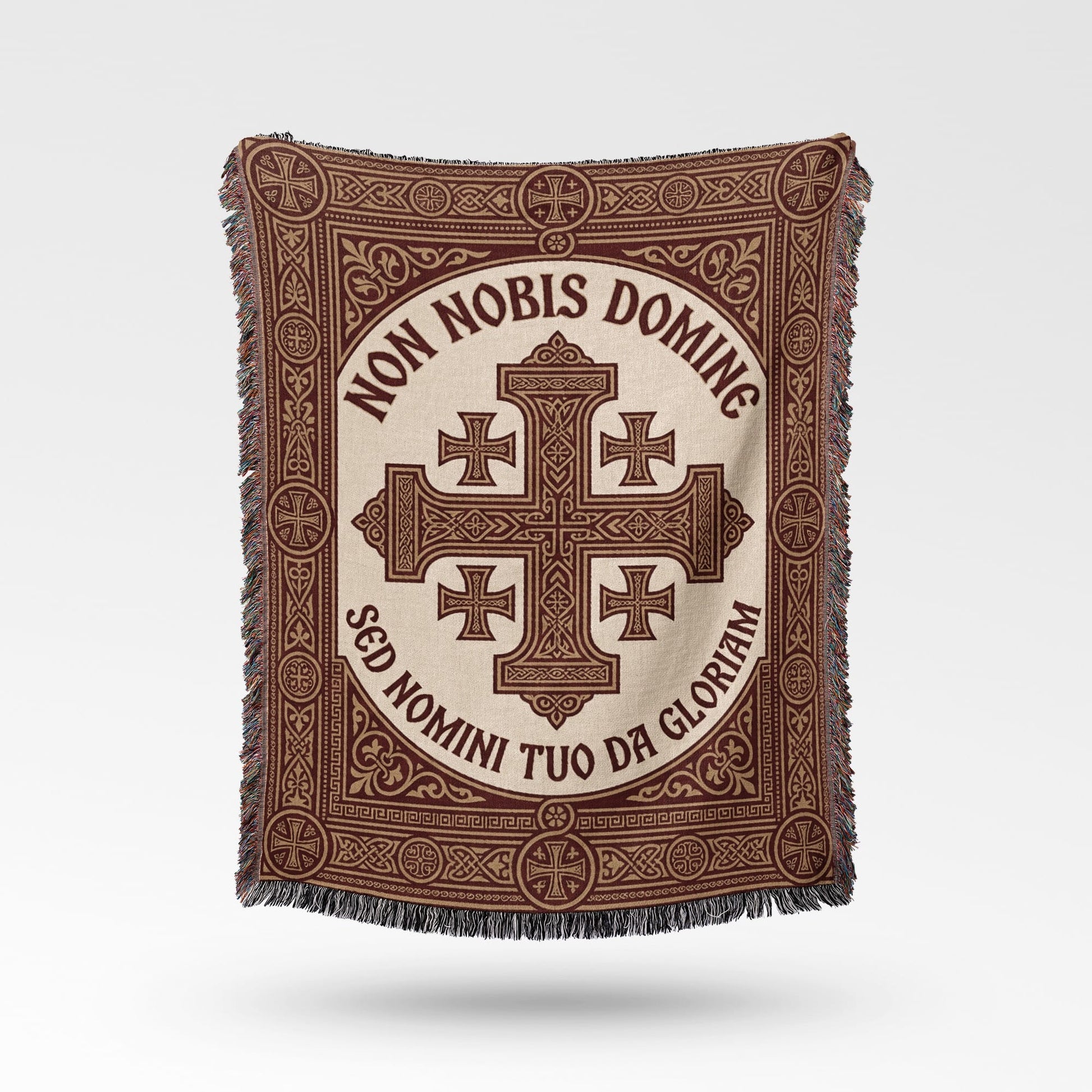 Text "Non Nobis Domine Sed Nomini Tuo Da Gloriam" on a woven throw with cross design.