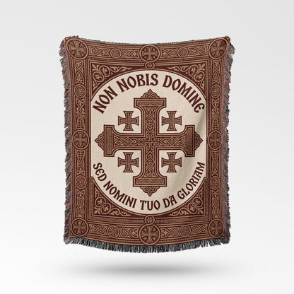 Text "Non Nobis Domine Sed Nomini Tuo Da Gloriam" on a woven throw with cross design.