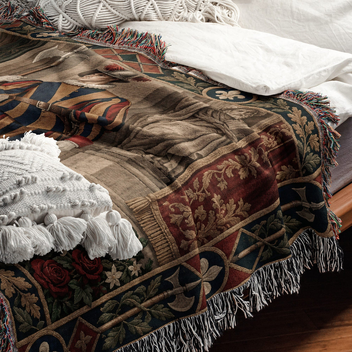 Woven throw blanket featuring a medieval-style portrait and floral borders, draped across a white-sheeted bed.