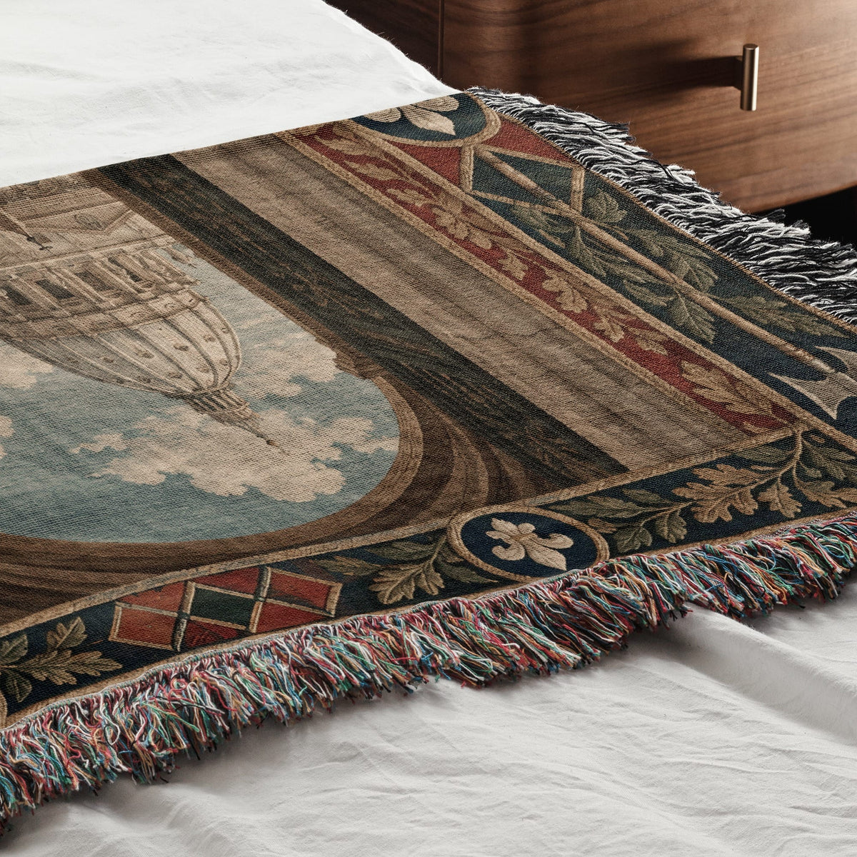 Woven throw blanket with a classical architectural design draped across a white bed.