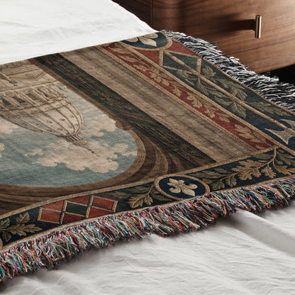 Woven throw blanket with a classical architectural design draped across a white bed.
