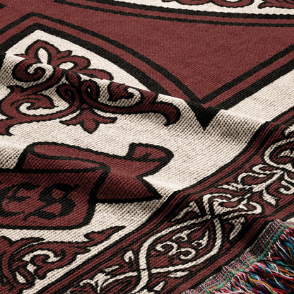 Maroon and cream woven blanket with ornate border and fringe detail.