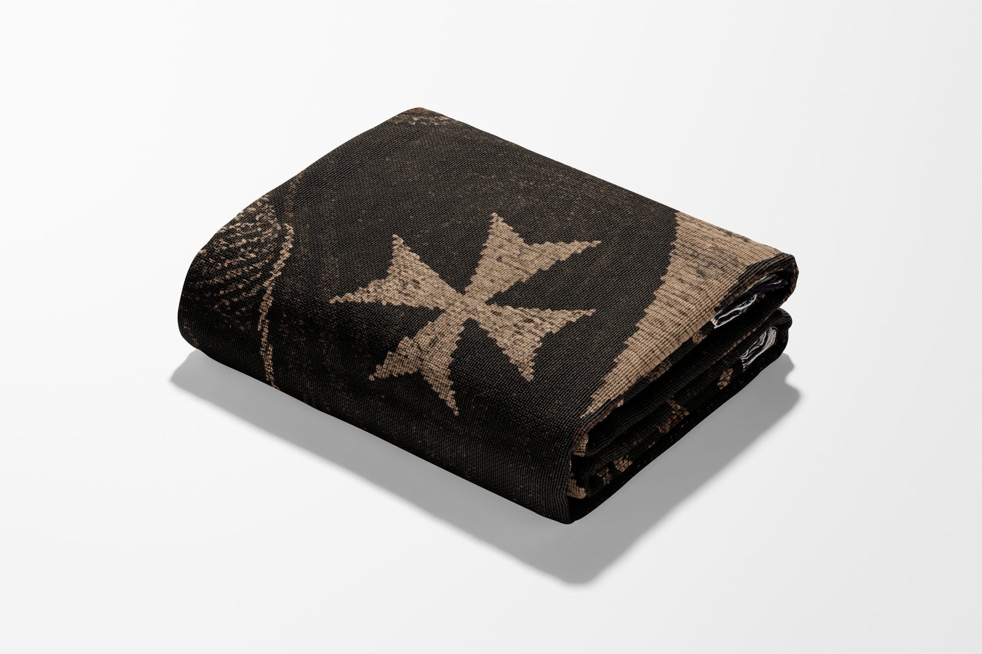 Folded dark blanket with a prominent light-colored cross pattern.