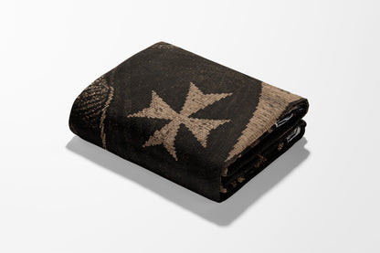 Folded dark blanket with a prominent light-colored cross pattern.