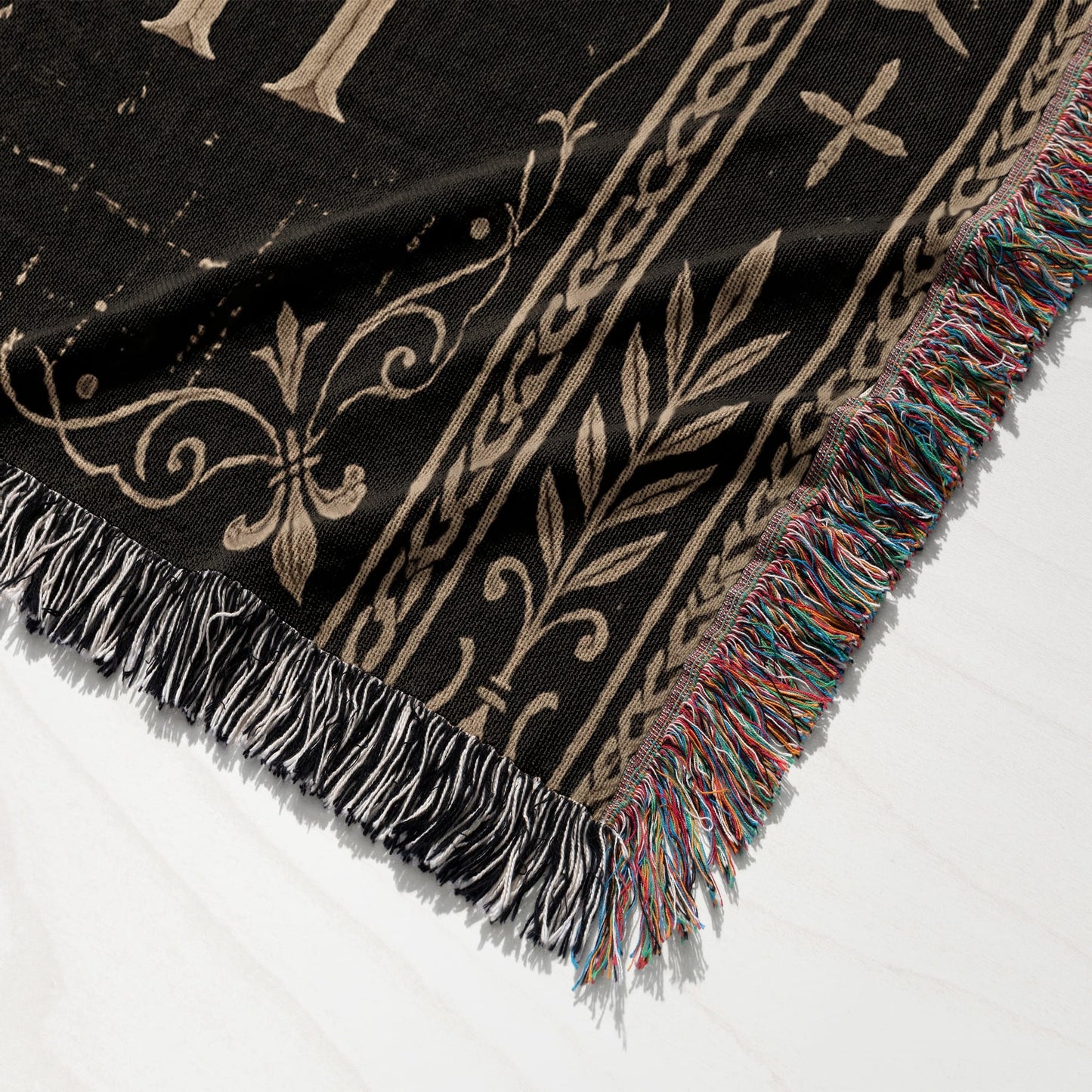 Black blanket with metallic gold scrollwork design and fringed edges.