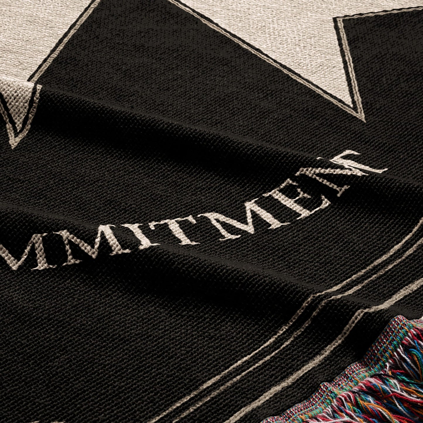 Black and white text reads "COMMITMENT" across a textured black fabric.