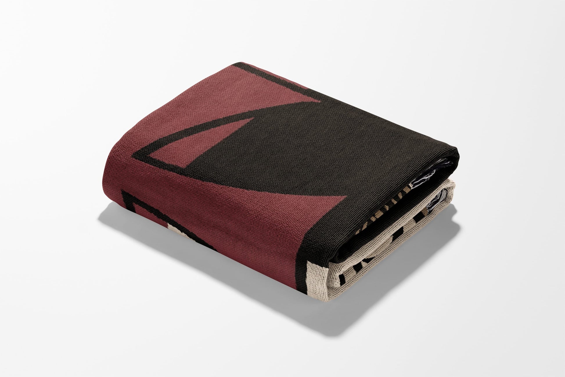 Folded blanket with abstract red and black geometric pattern.