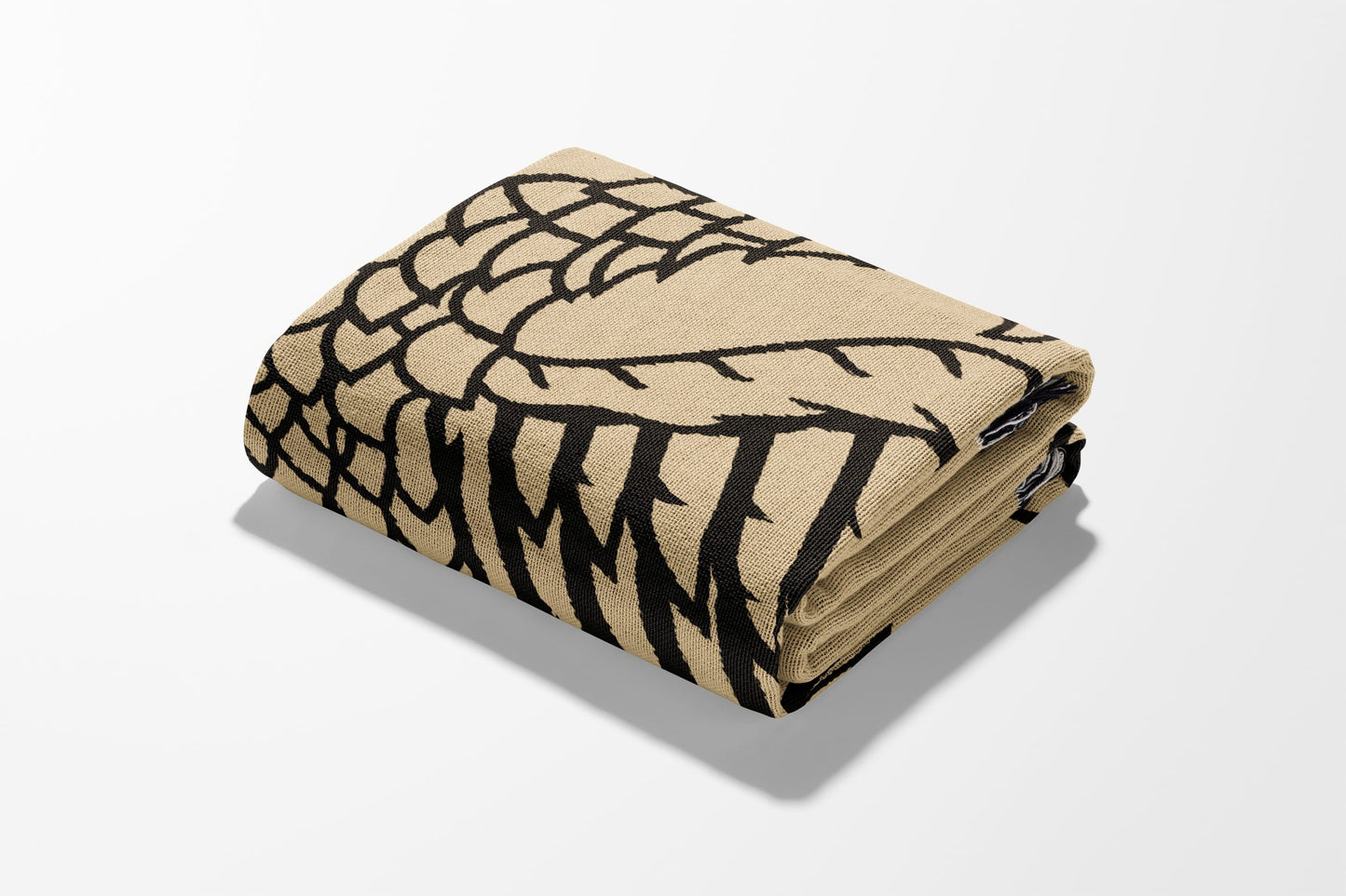 Folded beige throw blanket with black tribal-inspired pattern.