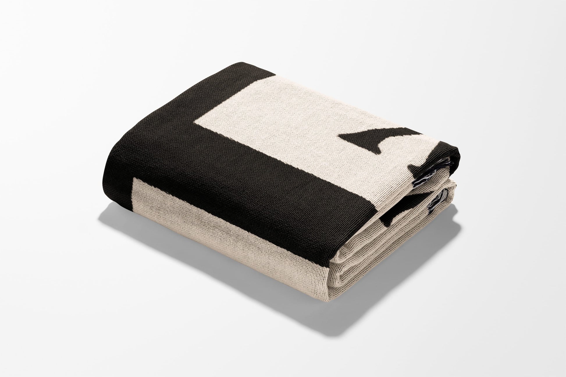 Folded black and cream blanket with letter 'L' design.
