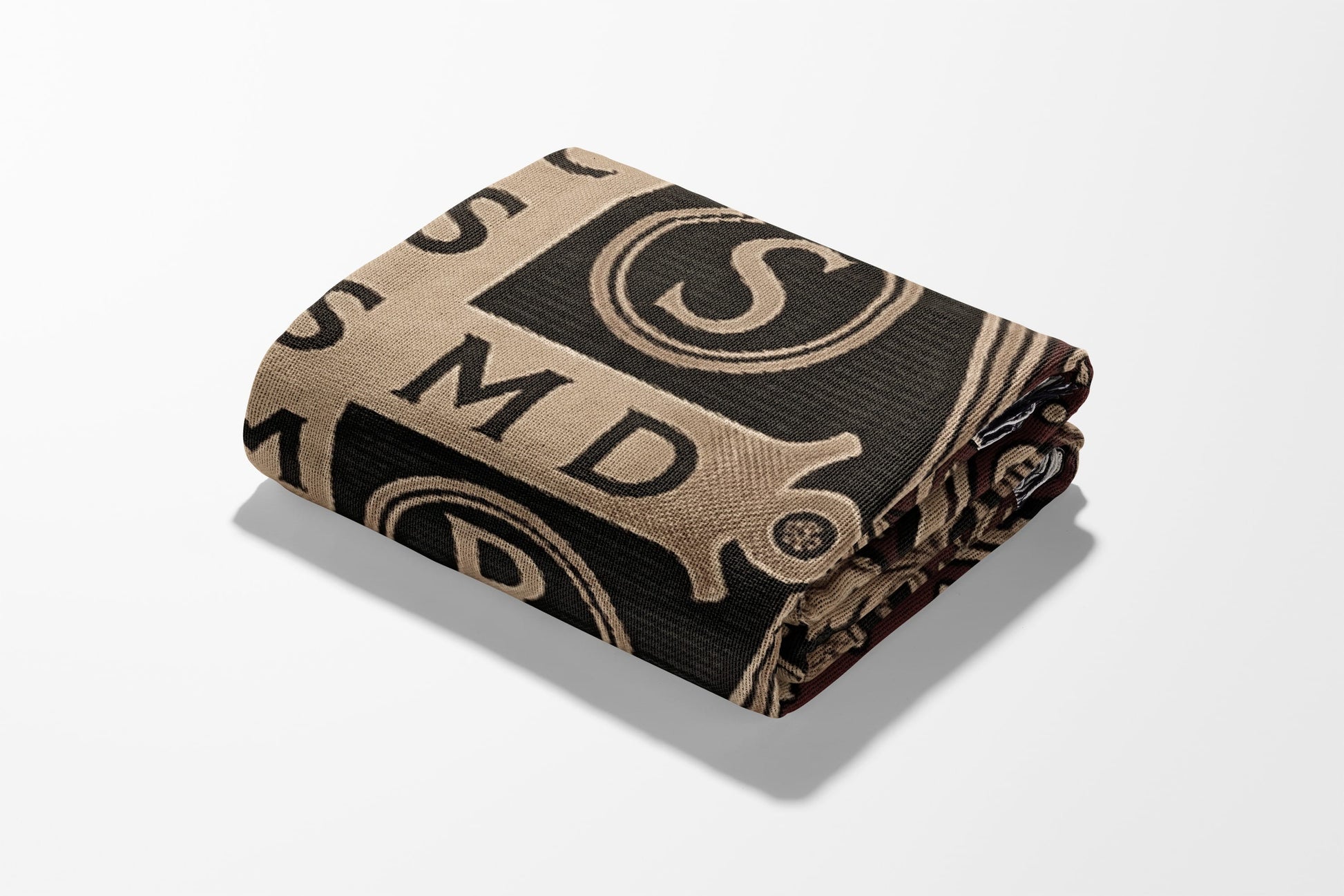 Folded blanket with beige and black pattern featuring letters and circles.
