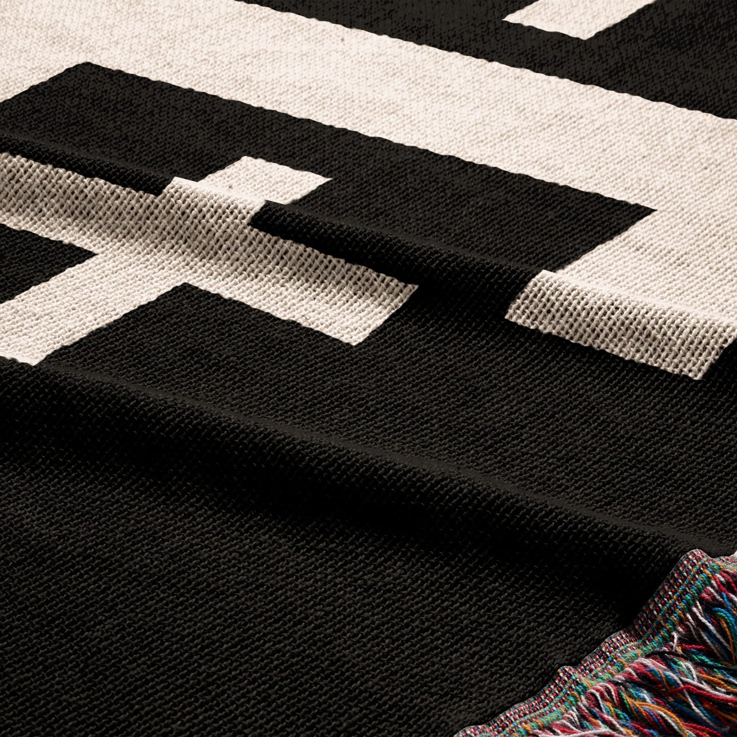 Black and white patterned throw blanket with fringed edges.
