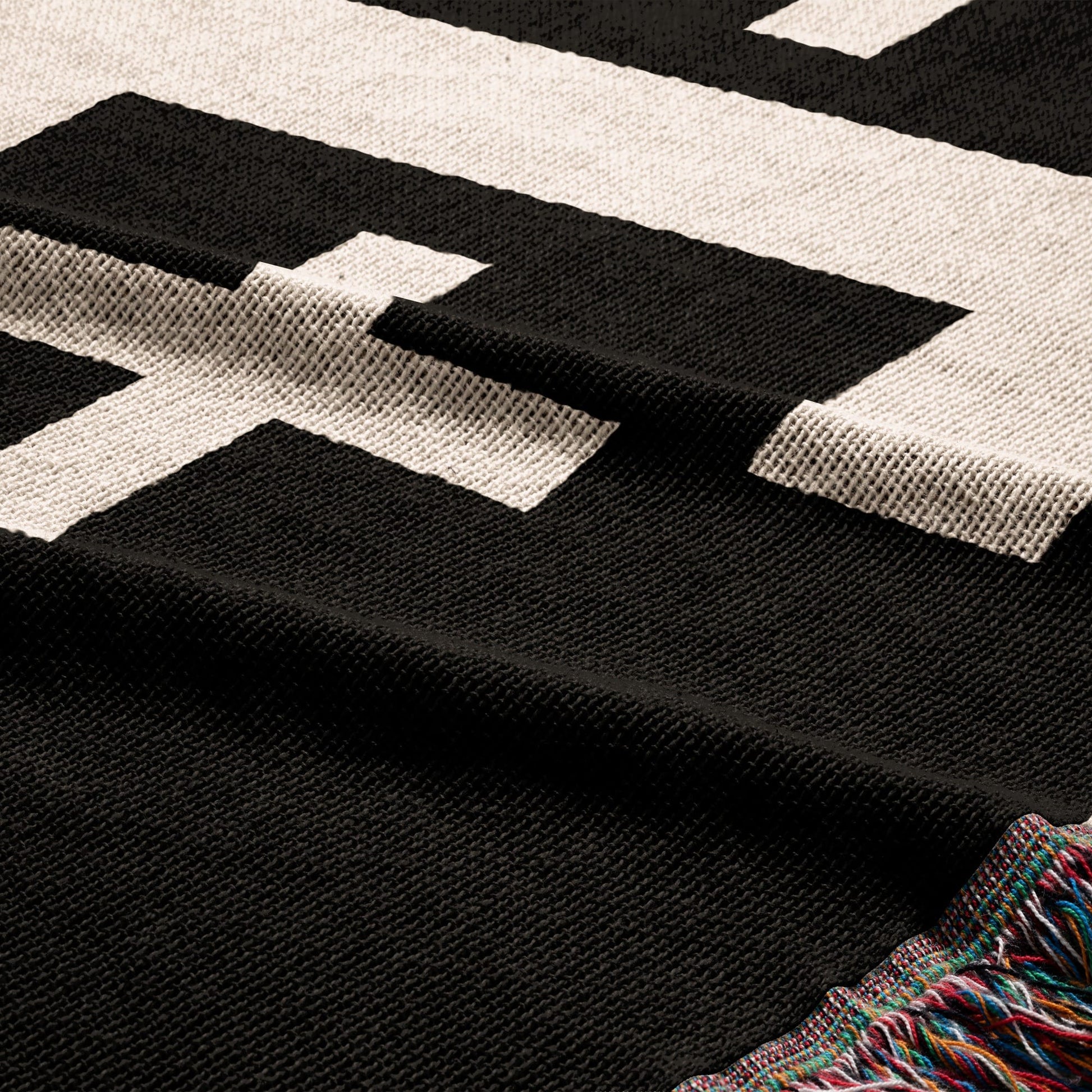 Black and white patterned throw blanket with fringed edges.