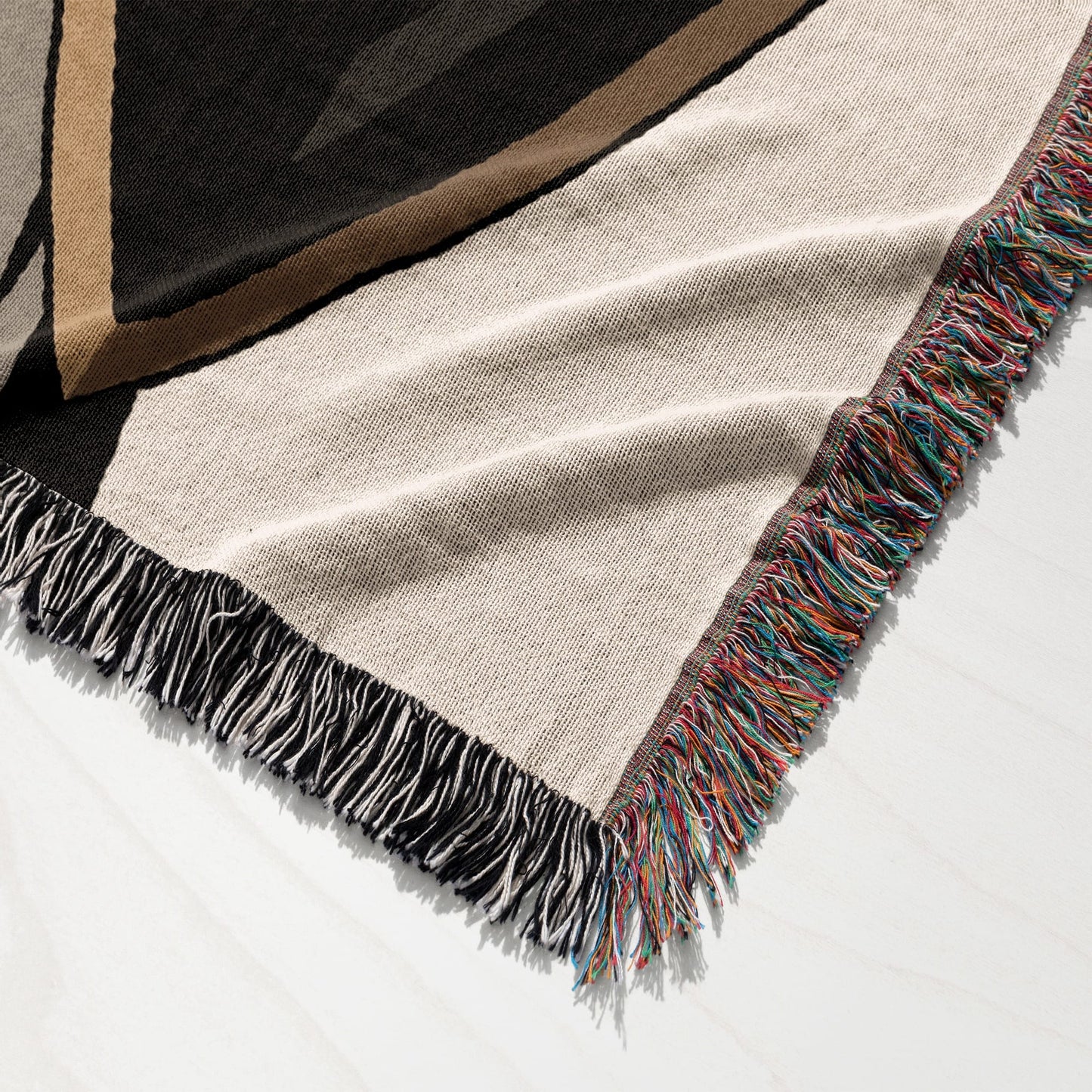 Tan blanket with colorful fringe and geometric pattern, folded.